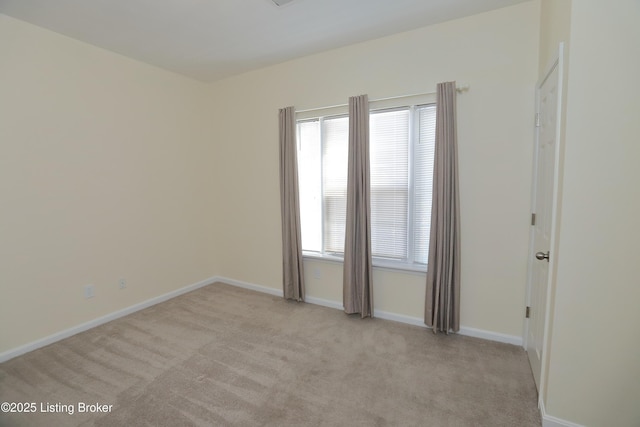 unfurnished room featuring light carpet and baseboards