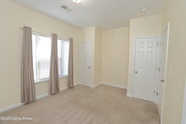 spare room featuring baseboards, visible vents, and light colored carpet