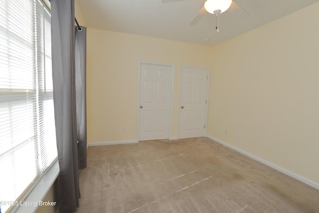 unfurnished bedroom featuring light carpet, baseboards, and a ceiling fan