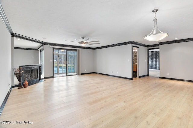 unfurnished living room featuring baseboards, light wood-style flooring, ceiling fan, crown molding, and a fireplace