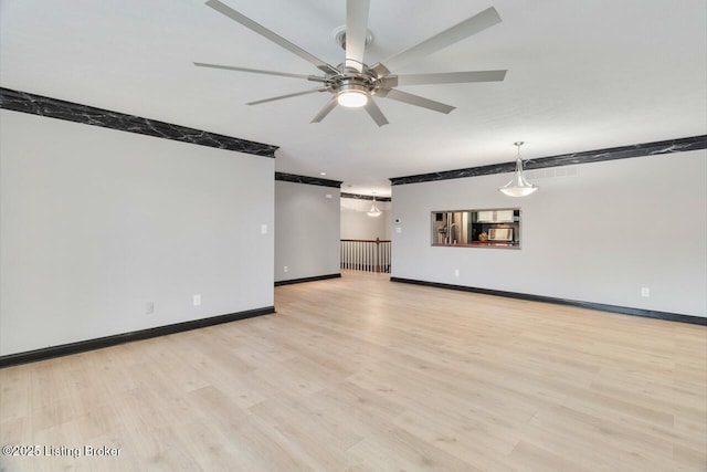 empty room featuring a ceiling fan, light wood-style flooring, and baseboards