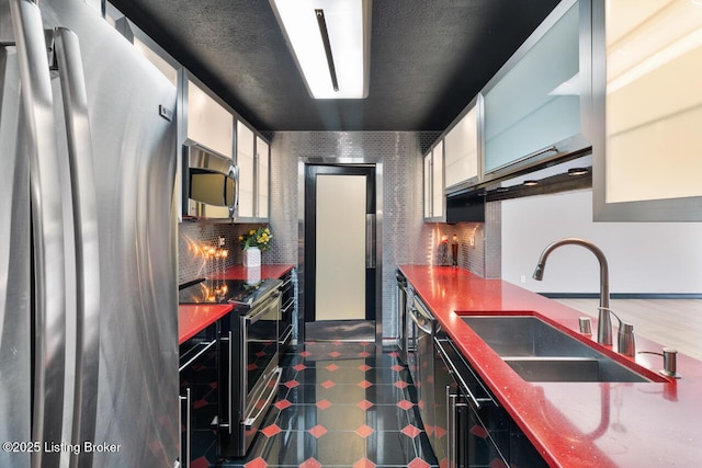 kitchen featuring appliances with stainless steel finishes, a sink, white cabinetry, and decorative backsplash