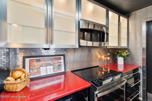 kitchen with glass insert cabinets, range with electric cooktop, stainless steel microwave, and backsplash