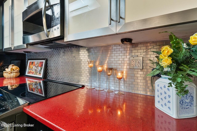 kitchen with stainless steel microwave, electric range, and decorative backsplash