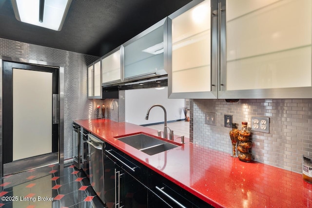 kitchen featuring a sink, white cabinets, stainless steel dishwasher, decorative backsplash, and glass insert cabinets