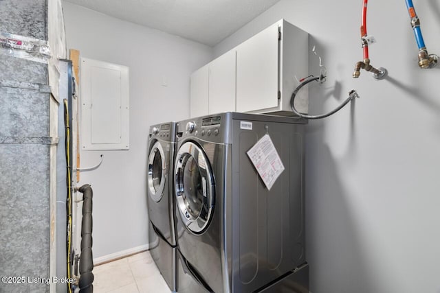 washroom with cabinet space, light tile patterned floors, electric panel, baseboards, and washing machine and dryer