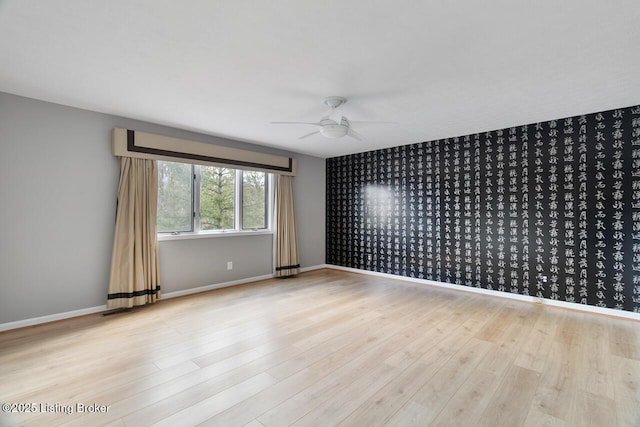 empty room with ceiling fan, baseboards, and wood finished floors