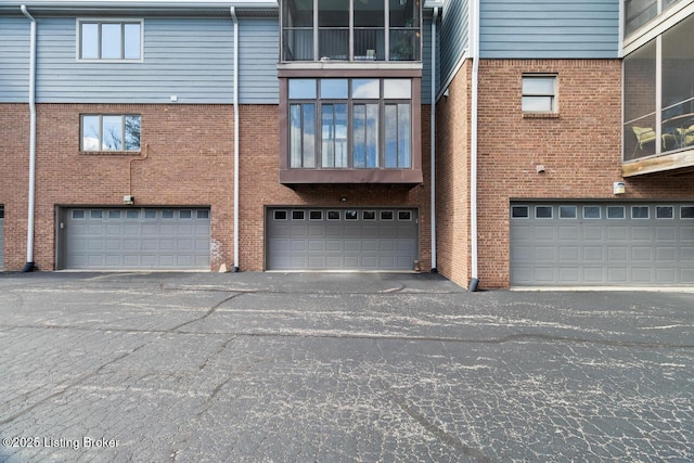 back of property with an attached garage, driveway, and brick siding