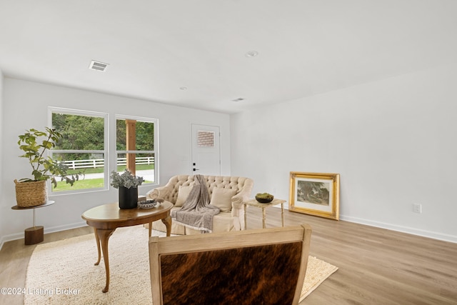 living area featuring baseboards, visible vents, and light wood finished floors