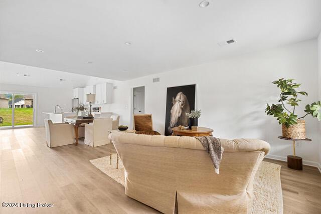 living room featuring light wood-type flooring, baseboards, and visible vents