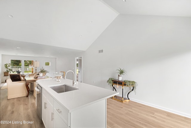 kitchen with a center island with sink, light wood-style flooring, stainless steel dishwasher, open floor plan, and a sink