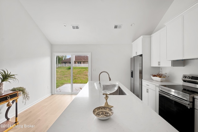 kitchen with appliances with stainless steel finishes, lofted ceiling, visible vents, and a sink