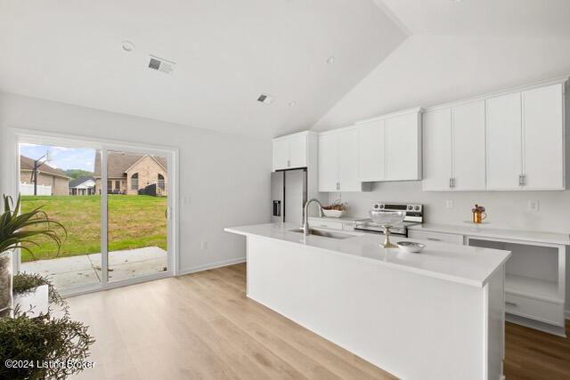 kitchen with a kitchen island with sink, stainless steel appliances, a sink, visible vents, and light countertops