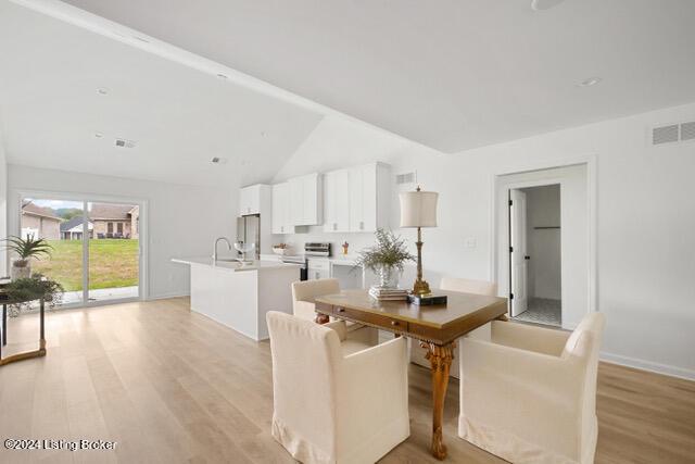 dining area featuring lofted ceiling, baseboards, visible vents, and light wood finished floors