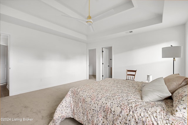 carpeted bedroom featuring a tray ceiling, visible vents, ceiling fan, and baseboards