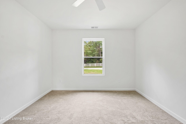 empty room with carpet floors, baseboards, visible vents, and ceiling fan