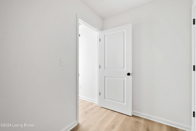 corridor featuring light wood-style flooring and baseboards