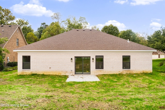 rear view of property with a patio area, a yard, and roof with shingles