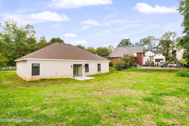 rear view of property featuring fence, a lawn, and brick siding