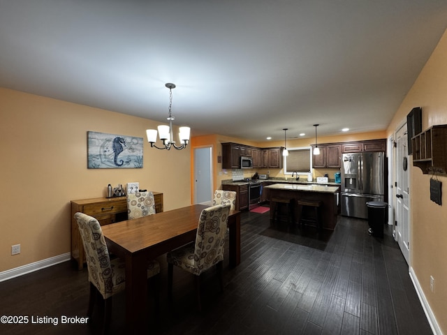 dining area with dark wood-style floors, a chandelier, and baseboards