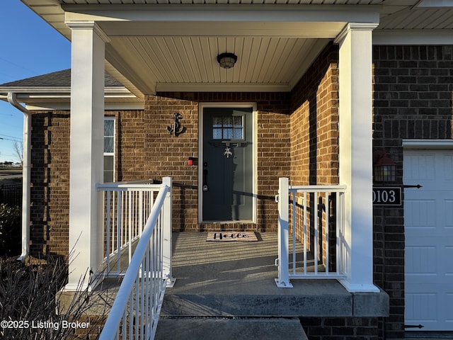 view of exterior entry featuring covered porch and brick siding