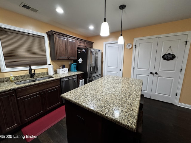 kitchen featuring stainless steel appliances, visible vents, hanging light fixtures, a sink, and dark brown cabinets