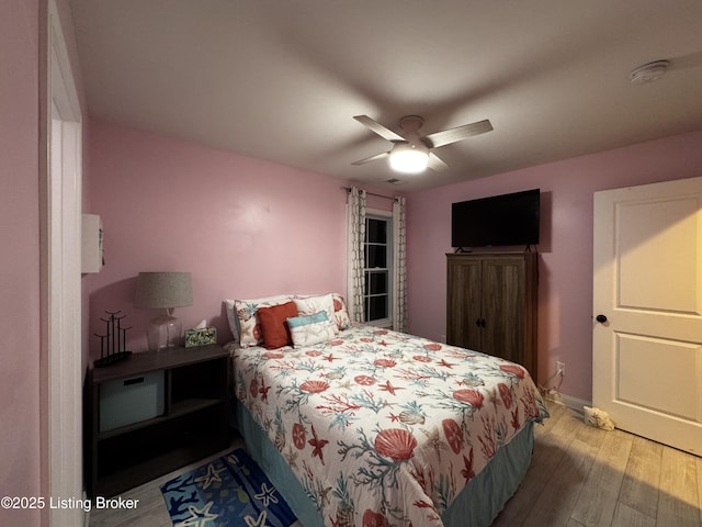 bedroom with ceiling fan, wood finished floors, and baseboards