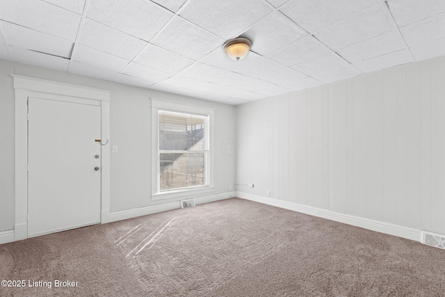 unfurnished room featuring carpet floors, baseboards, visible vents, and a paneled ceiling