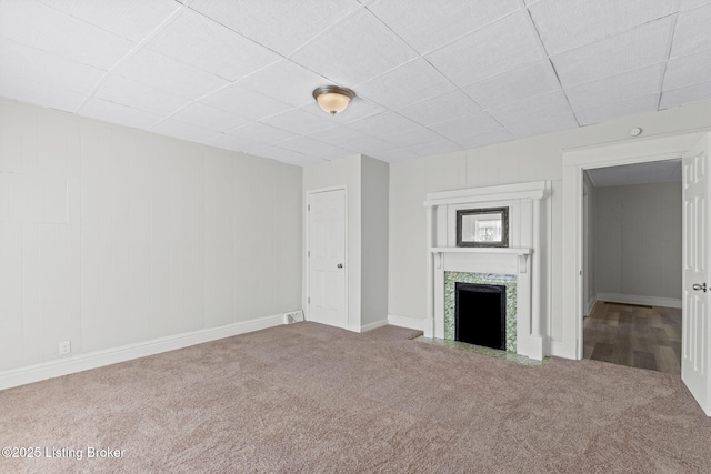 unfurnished living room featuring carpet, a fireplace, visible vents, and baseboards