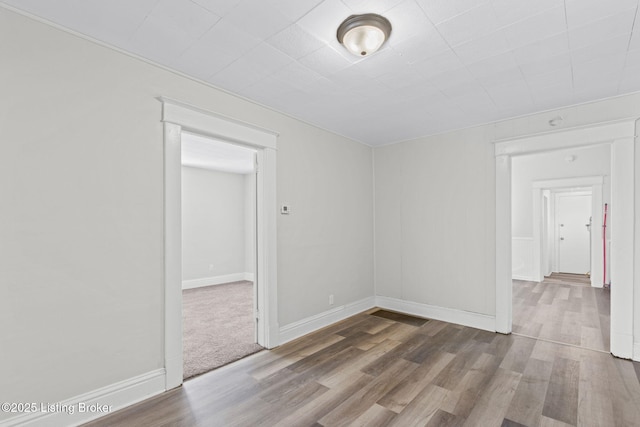 spare room featuring baseboards and wood finished floors