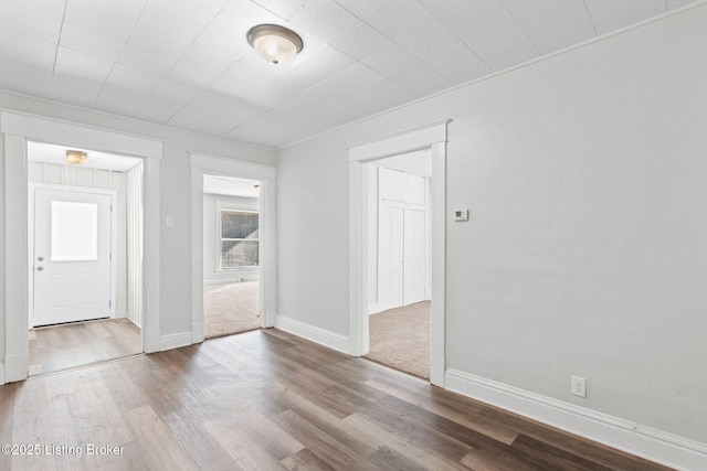 spare room with baseboards and wood finished floors