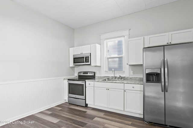 kitchen with appliances with stainless steel finishes, dark wood finished floors, white cabinets, and a sink