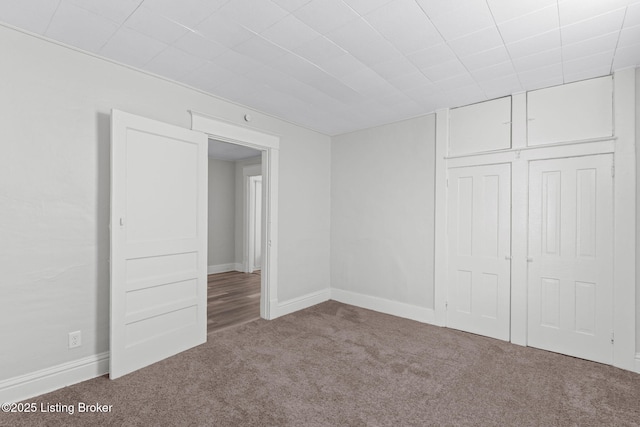 unfurnished bedroom featuring a closet, baseboards, and carpet flooring