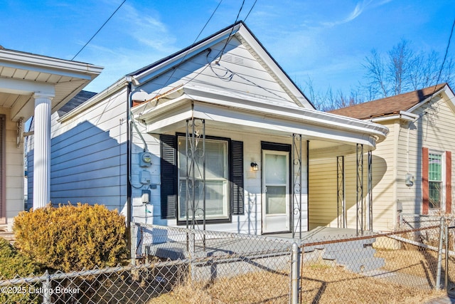 shotgun-style home featuring covered porch and a fenced front yard