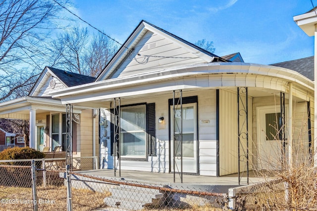 view of front of home featuring a porch, a shingled roof, and a fenced front yard