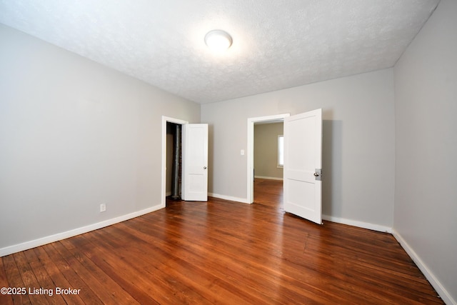 unfurnished room with baseboards, a textured ceiling, and hardwood / wood-style floors