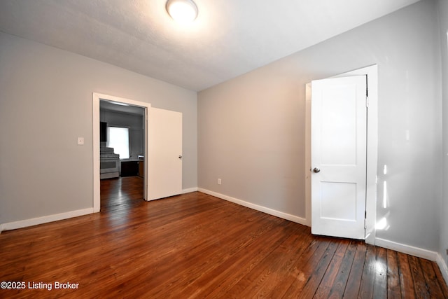 empty room featuring wood-type flooring and baseboards