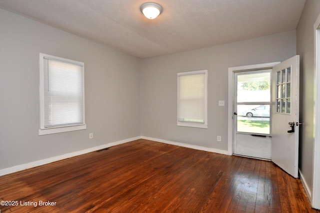 spare room featuring visible vents, baseboards, and hardwood / wood-style flooring