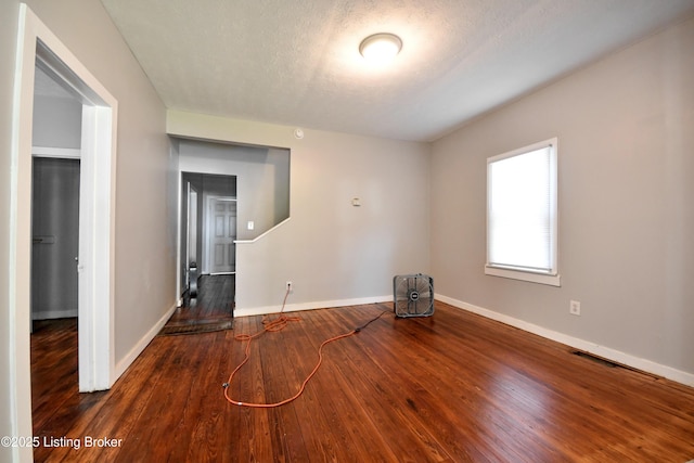 empty room with wood-type flooring, a textured ceiling, and baseboards