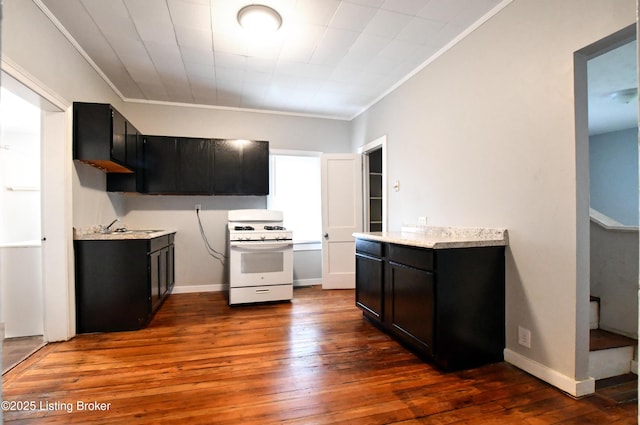 kitchen with dark wood finished floors, white gas range, crown molding, dark cabinetry, and a sink