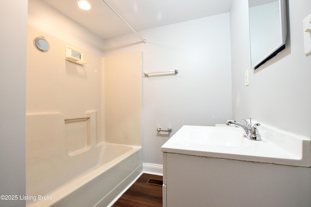 bathroom with visible vents, vanity, wood finished floors,  shower combination, and baseboards