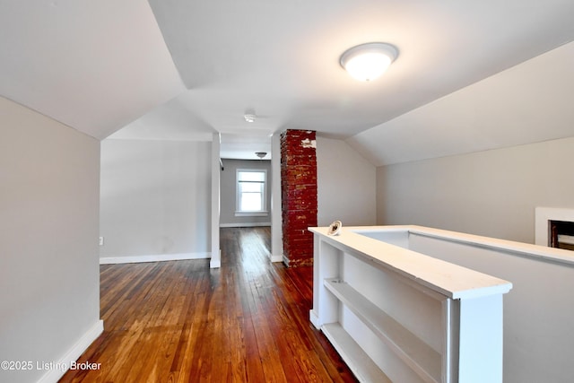 additional living space featuring dark wood-style flooring, vaulted ceiling, and baseboards