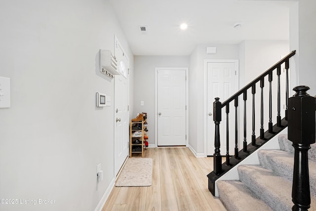 entrance foyer with light wood-style flooring, stairs, baseboards, and visible vents