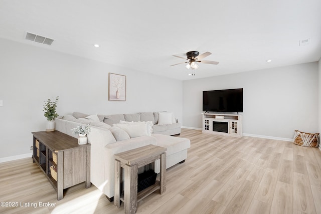 living room with light wood finished floors, visible vents, and baseboards