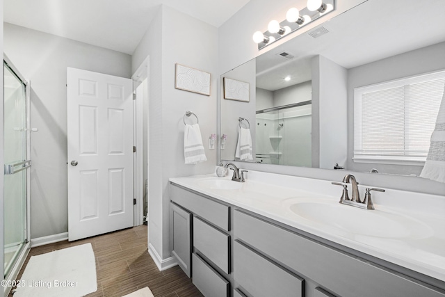 bathroom with wood finished floors, a stall shower, a sink, and visible vents