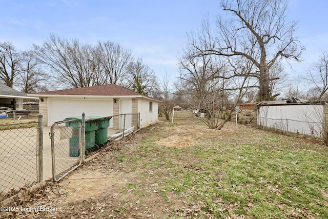 view of yard featuring a gate, a detached garage, fence, and an outdoor structure