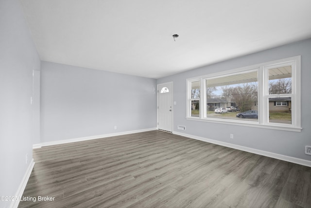 unfurnished living room featuring baseboards and wood finished floors