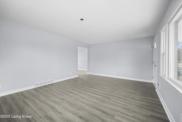 empty room featuring baseboards, visible vents, and wood finished floors