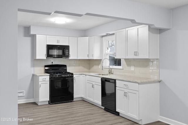 kitchen with black appliances, light stone counters, white cabinets, and a sink