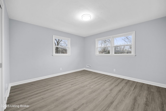 unfurnished room featuring plenty of natural light, wood finished floors, and baseboards